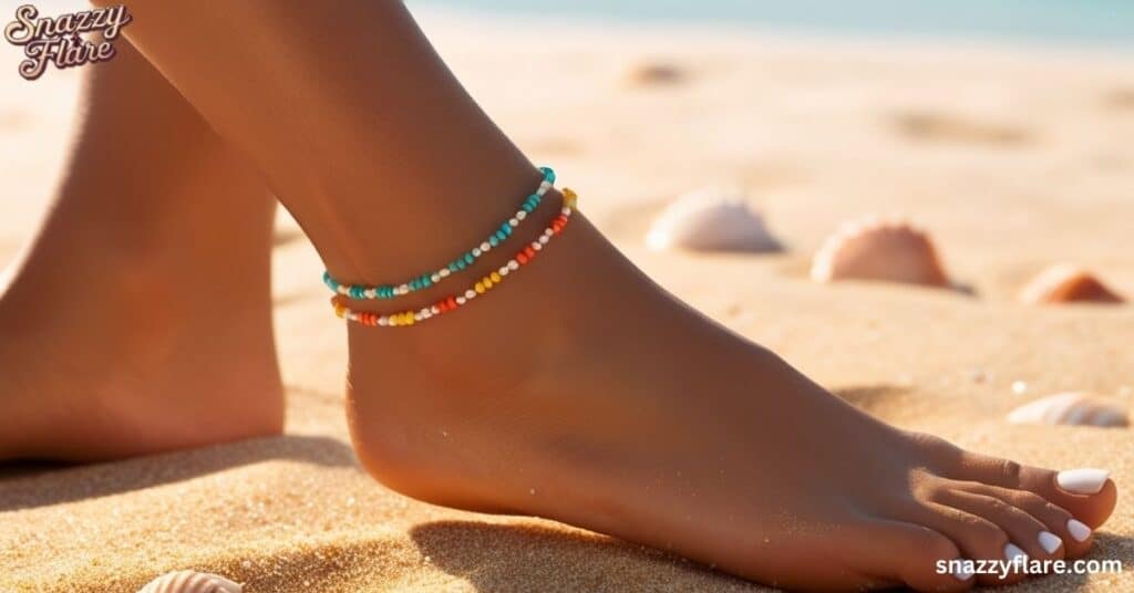 Close-up of foot on beach wearing colorful beaded anklets with seashells in the background