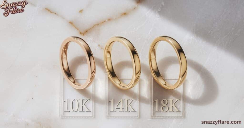 Three gold rings labeled 10K, 14K, and 18K on a marble surface with 'snazzyflare.com' in the corner