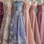 Row of elegant evening gowns in pastel colors and intricate designs on mannequins