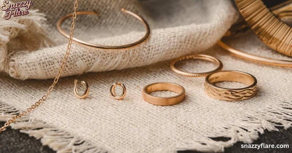 Gold jewelry including rings, earrings, and bracelets on a textured fabric surface