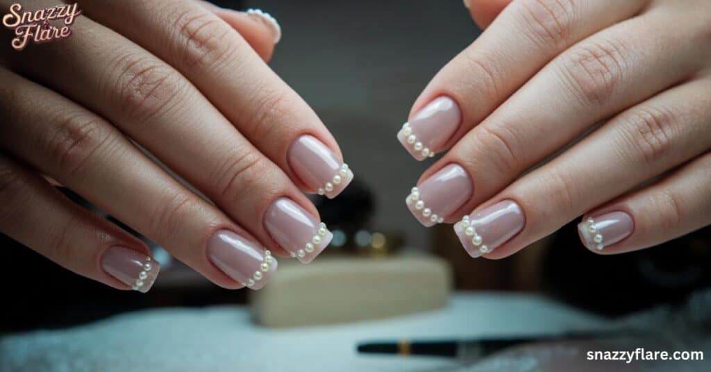 Close up of hands with nude nails adorned with small pearl decorations along the tips