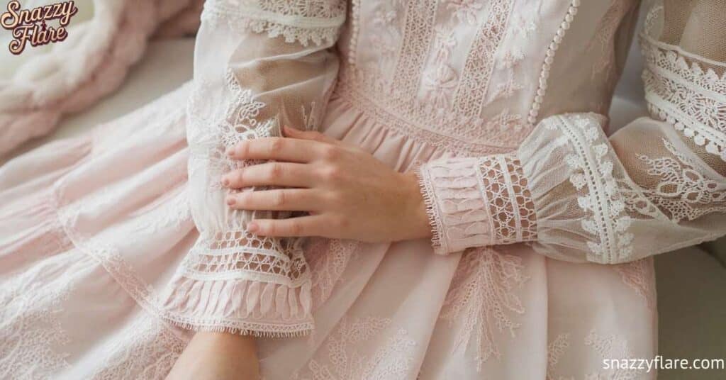 Close-up of hands resting on a pink lace dress with intricate embroidery and sheer sleeves