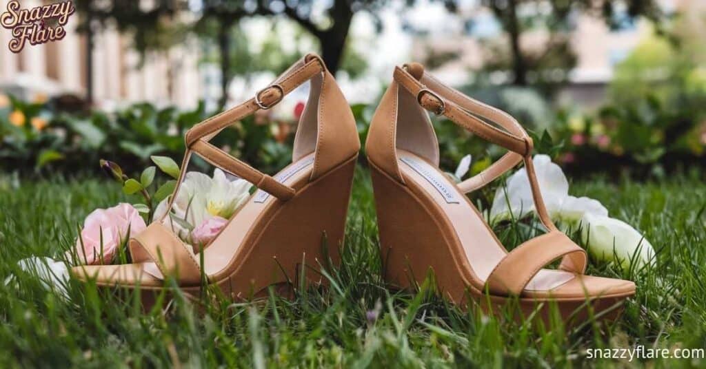 an wedge sandals with ankle straps placed on grass with flowers in the background