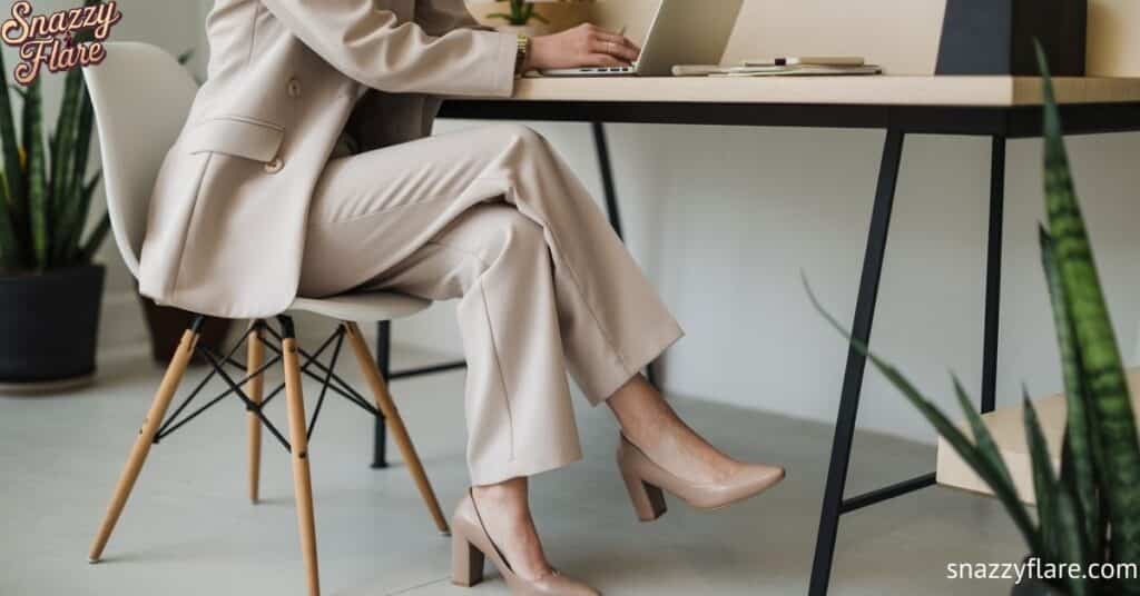 Person in beige suit working on a laptop at a desk with plants around