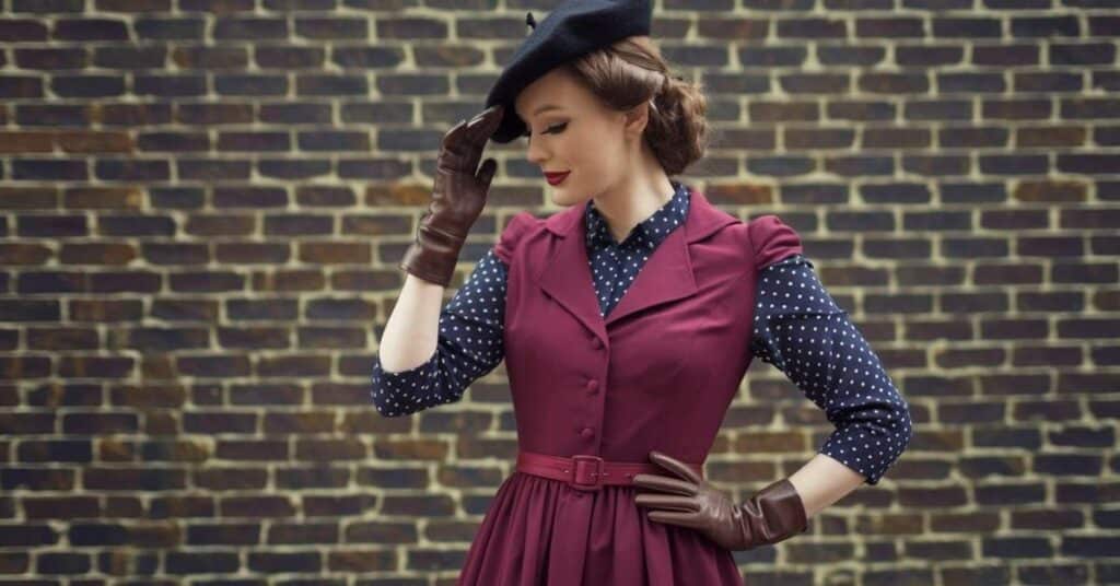 A woman in a 1940s-inspired A-line dress with polka dots and structured shoulders, styled with kitten heels and a beret.