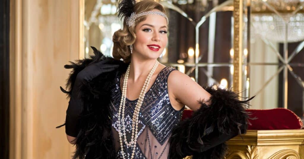 A woman wearing a sequined flapper dress, with a feather boa and a long pearl necklace, posing in a glamorous setting.